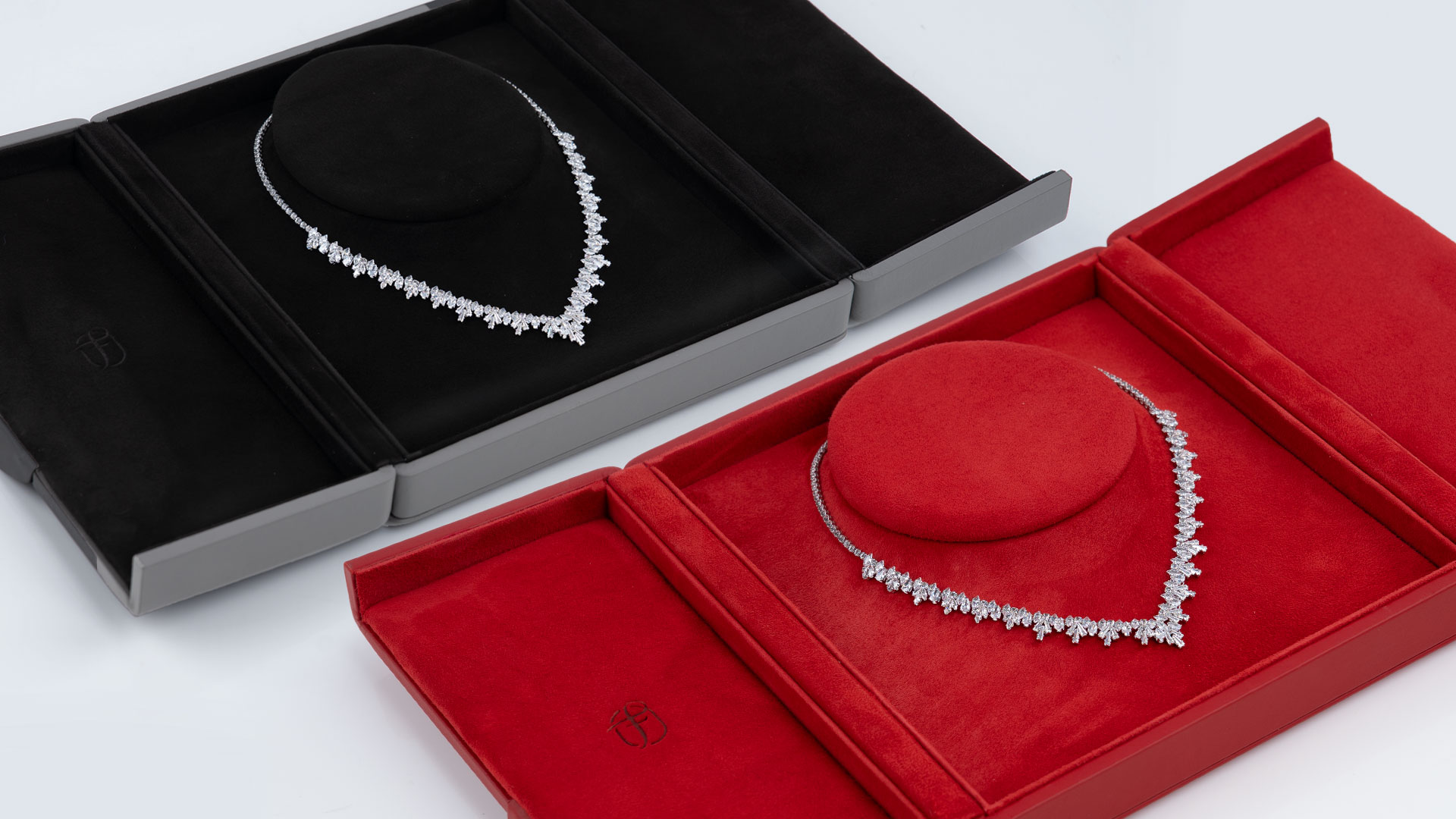 Two open Fleur de Luxe necklace cases in black-grey and red with jewellery necklace