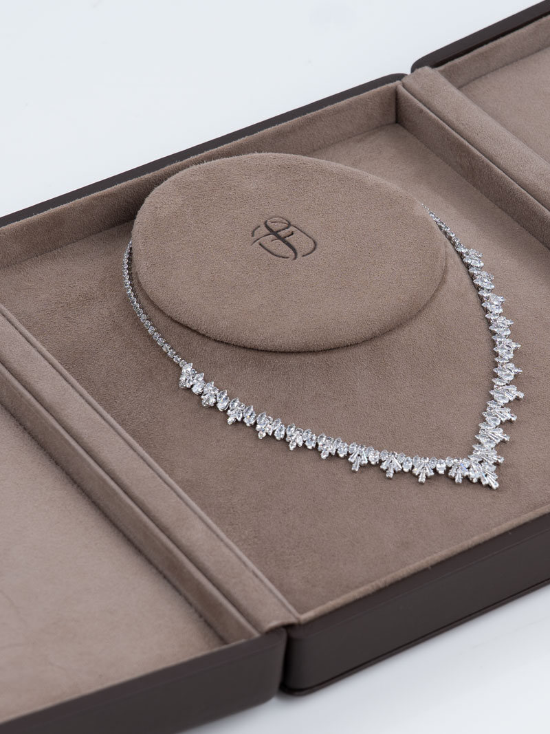 Detail of an open Fleur de Luxe necklace case in brown with bust inlay and blind embossed logo with diamond necklace